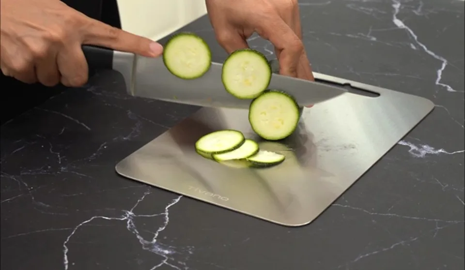 Fresh zucchini being sliced on a Tivano cutting board